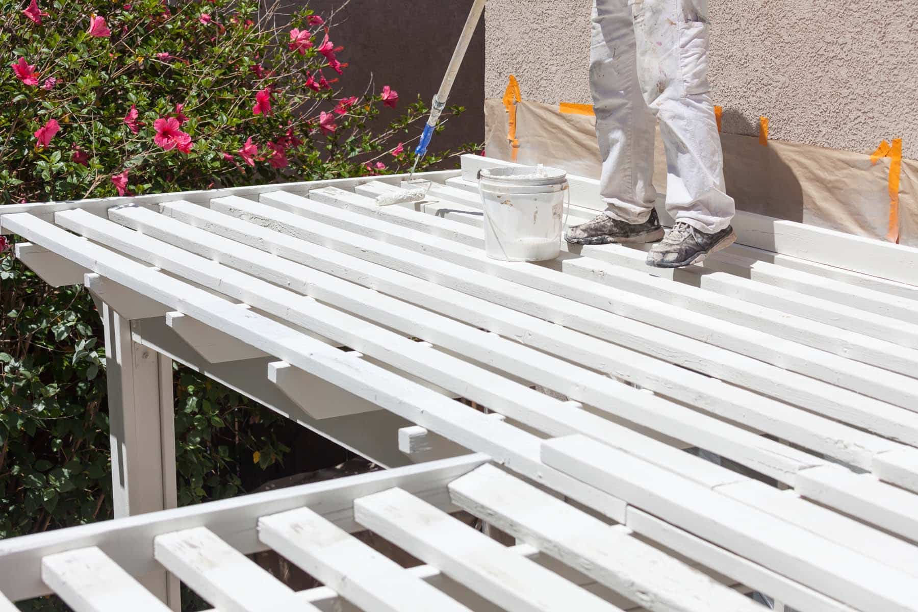 A wood deck being coated with a roller on an extension pole