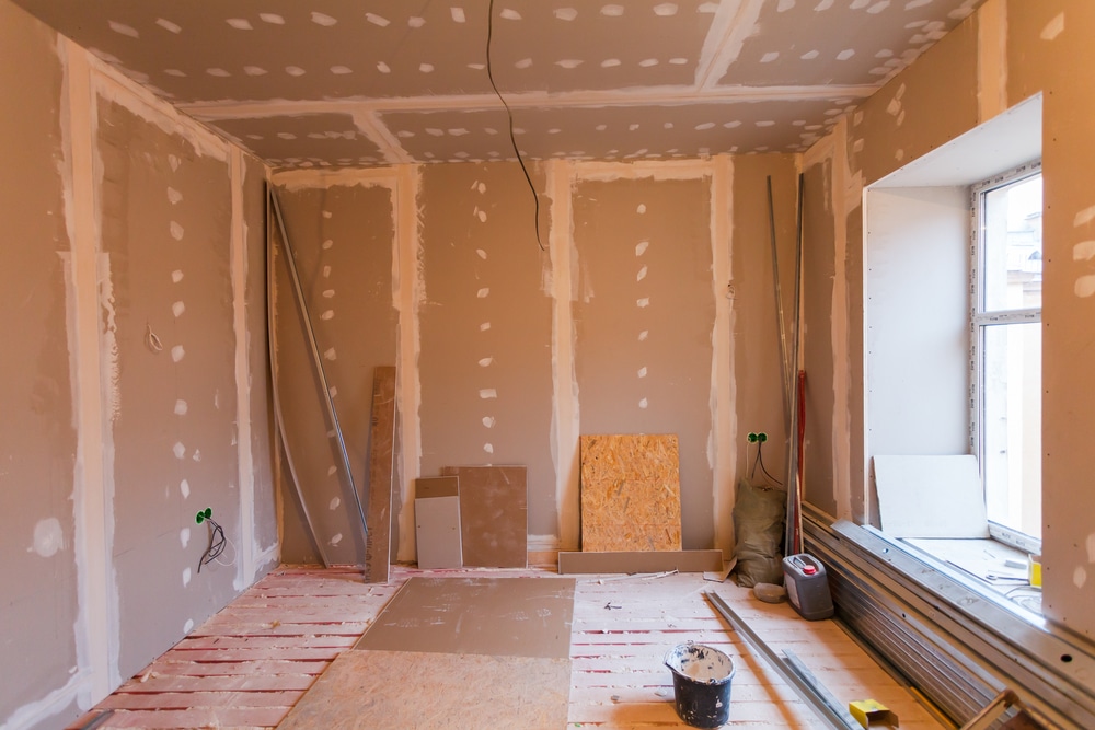 An empty room under dust sheets part way through painting