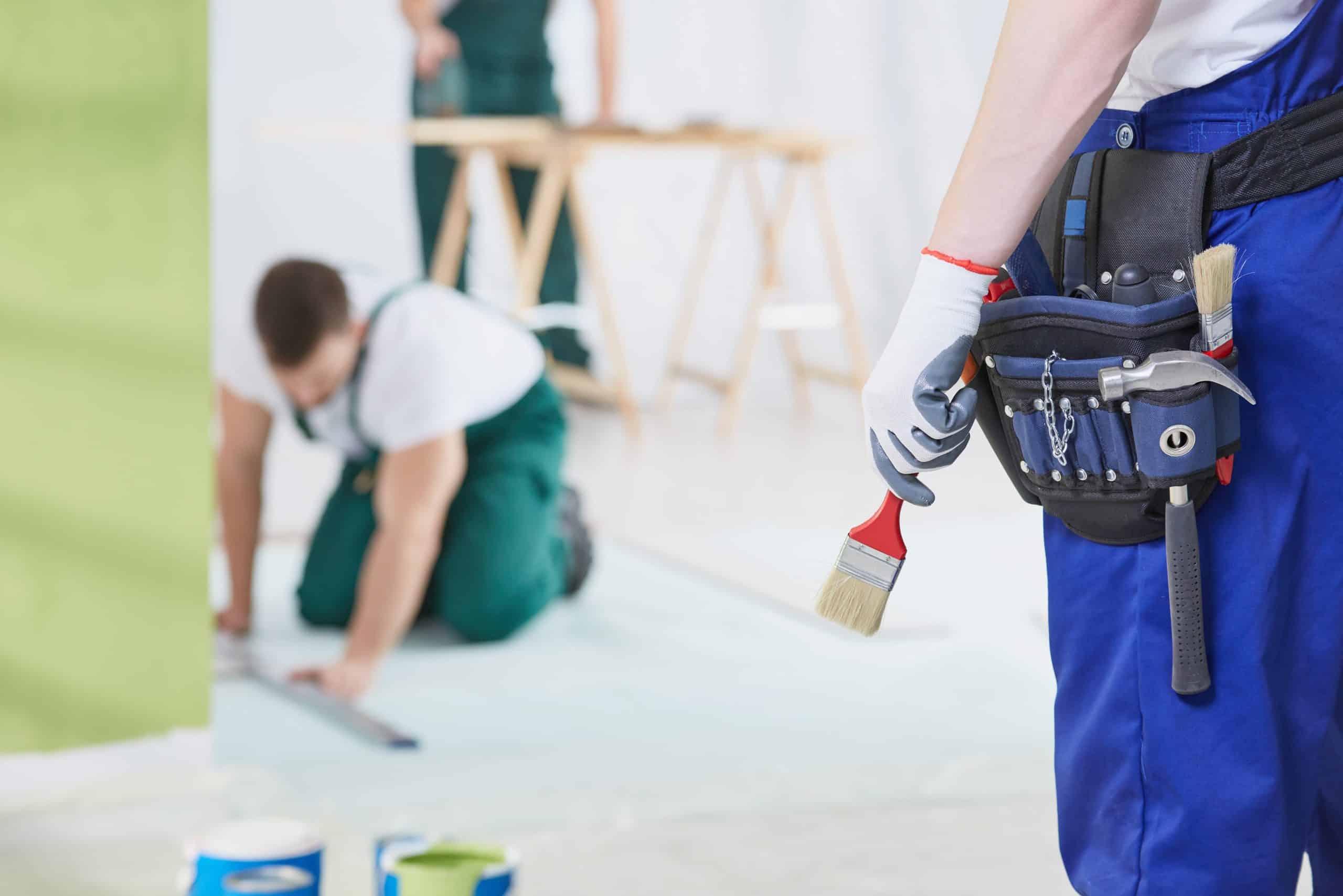 Two painters cutting in along an interior wall