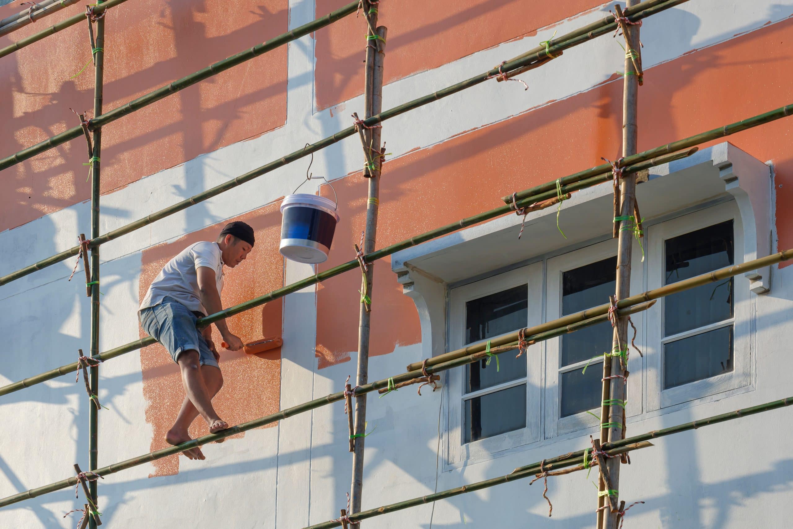 A painter on a scaffold working across the outside of a large building