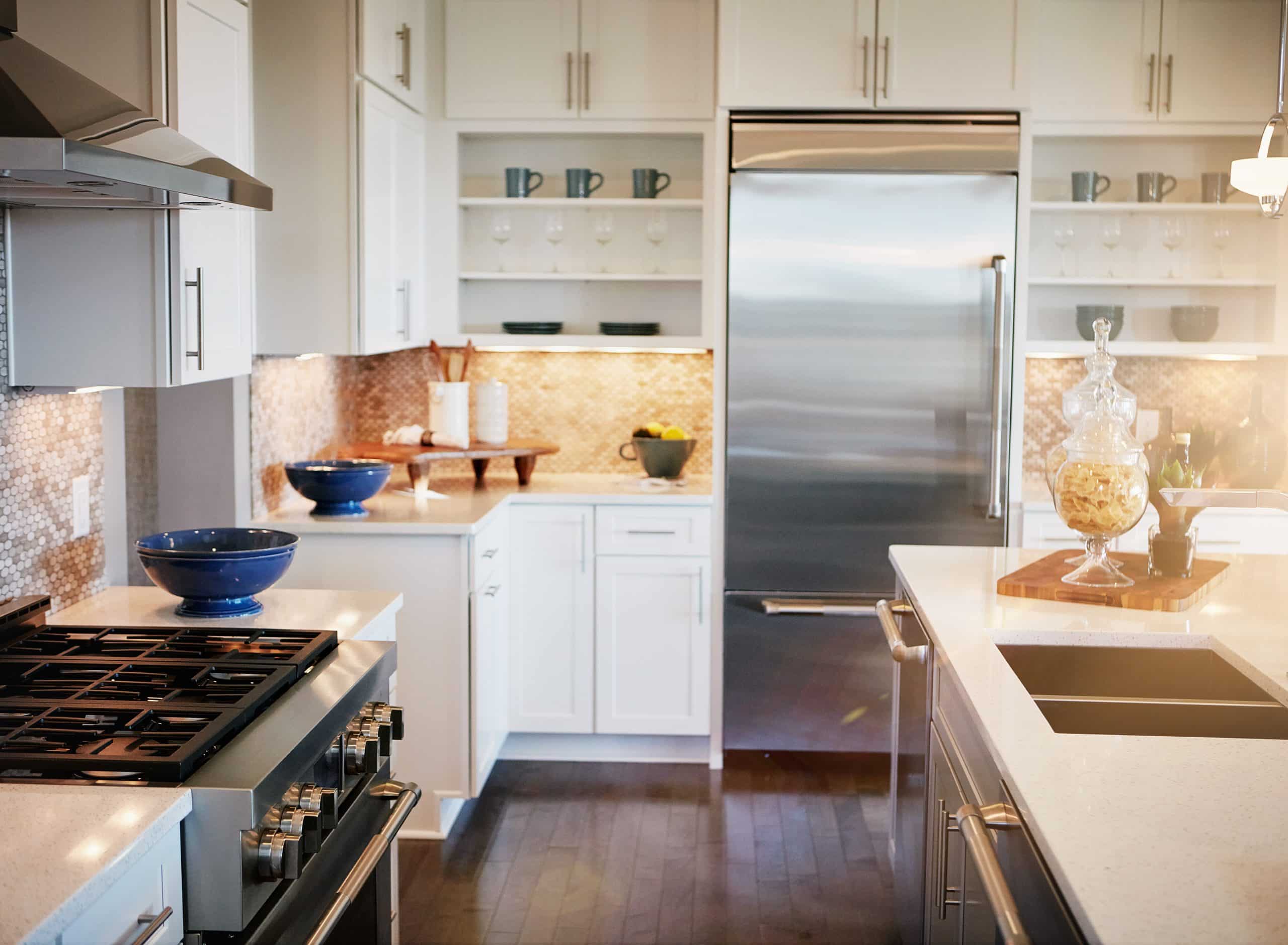 A finished kitchen with pale cabinets and a tiled splashback