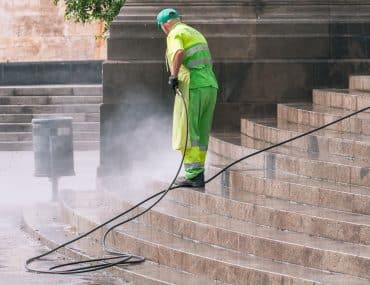 Worker pressure washing an outdoor surface