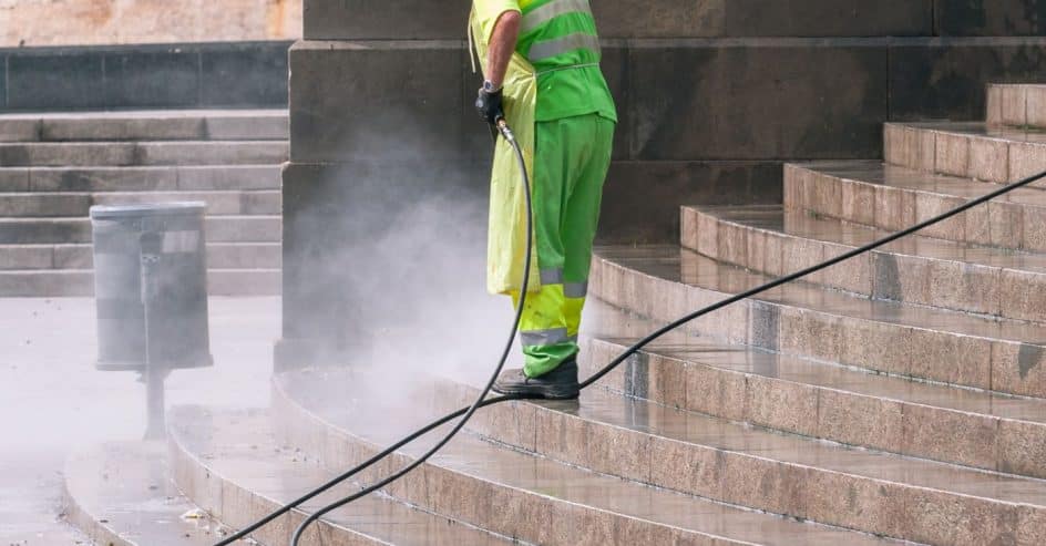 Worker pressure washing an outdoor surface