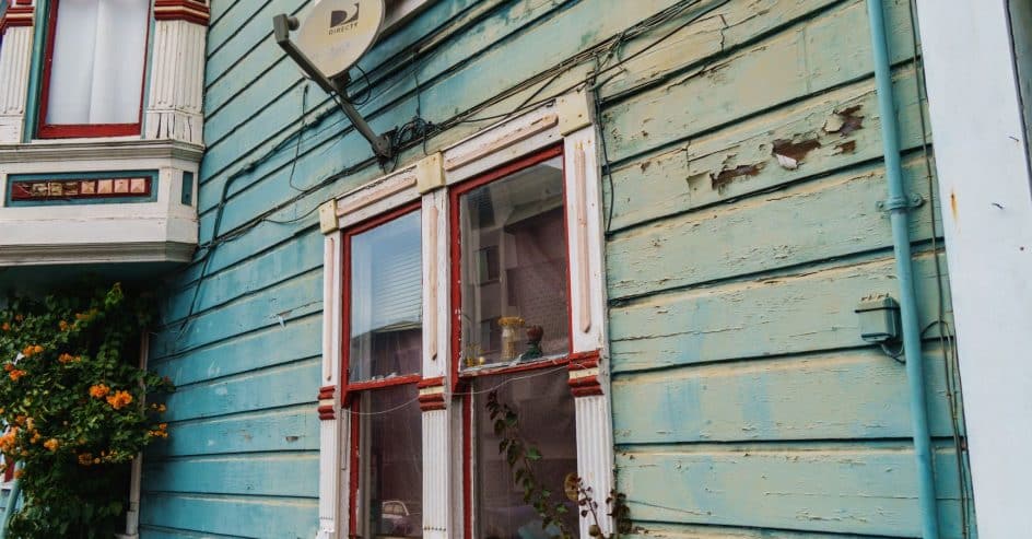 Aged, peeling paint on a wooden home exterior due for repainting