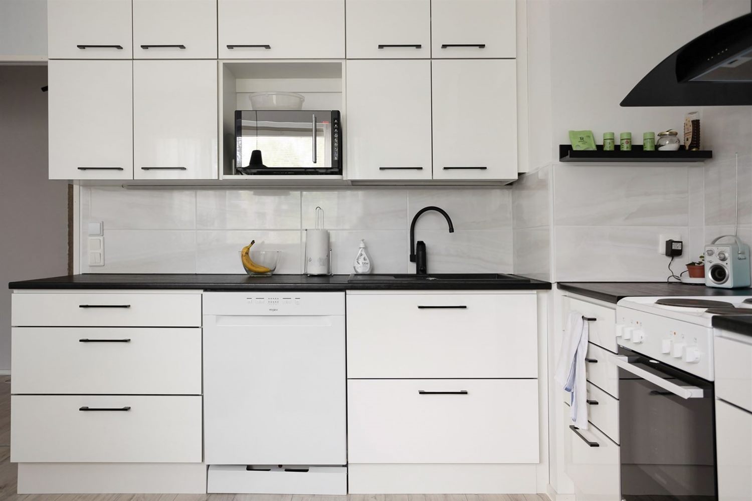A fitted kitchen with white cabinet doors and dark worktops