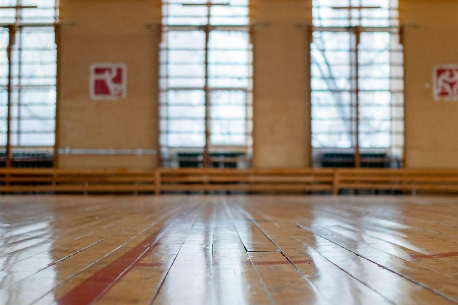 A sunlit gymnasium floor with tall windows along one wall
