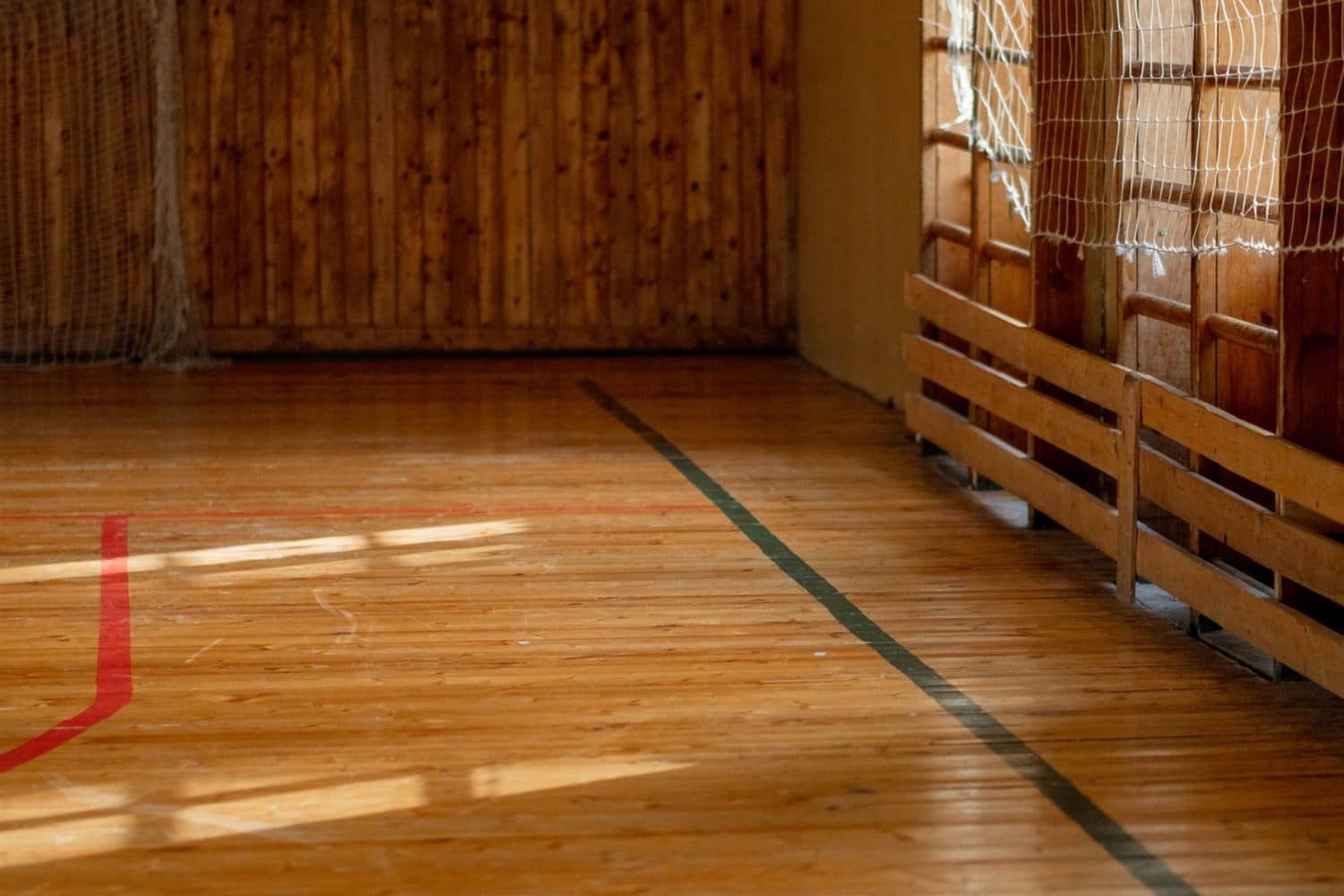 A polished gymnasium floor with wall bars and benches