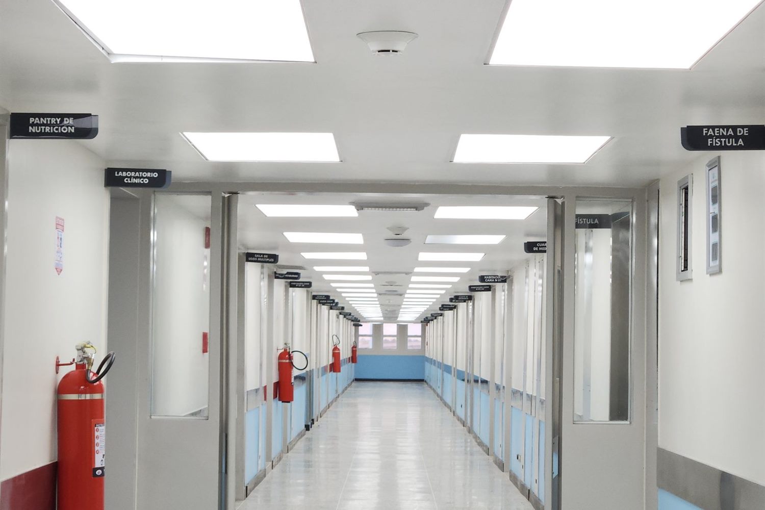 A bright hospital corridor with a fire extinguisher on the wall