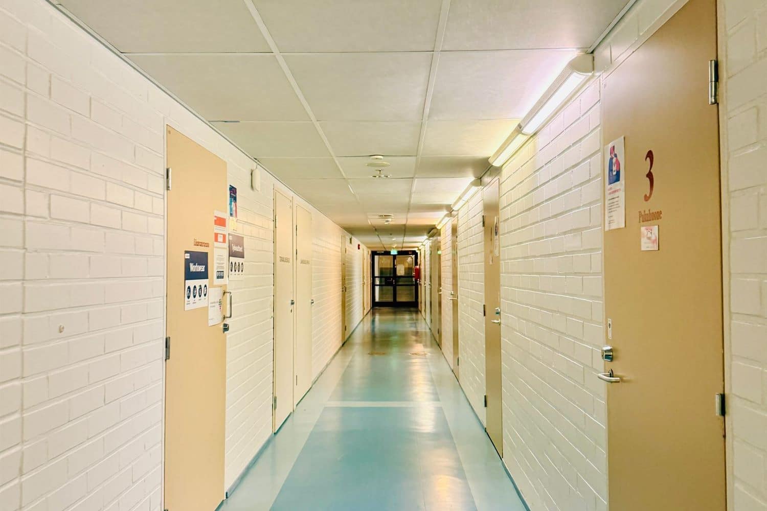 A clinical corridor with pale green walls and doors