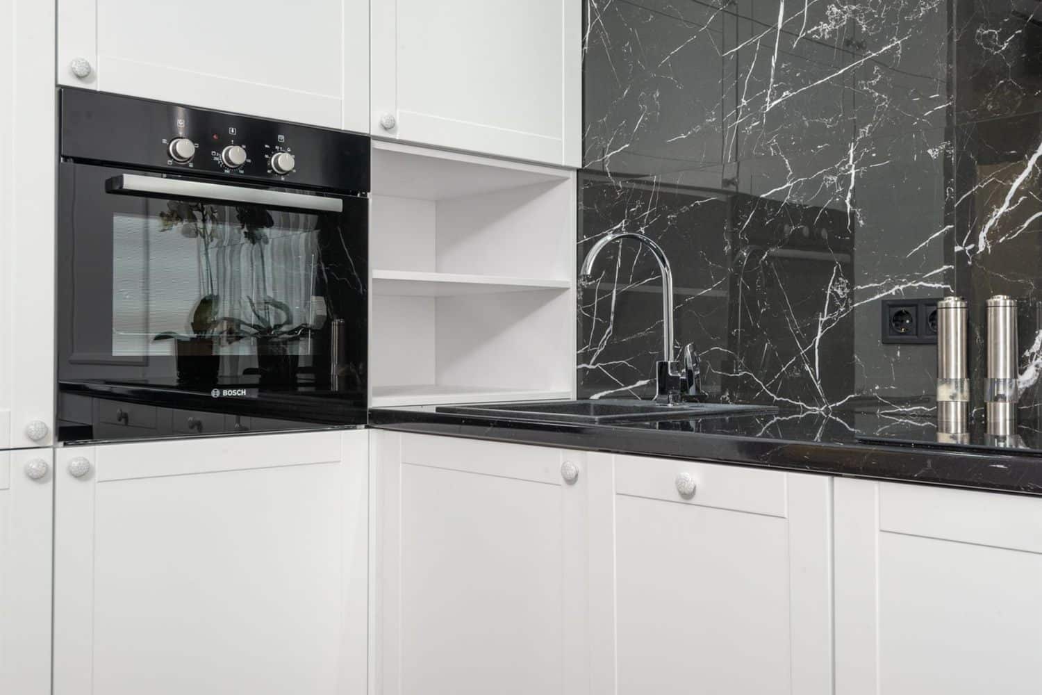 A kitchen run with dark cabinets and a marble splashback