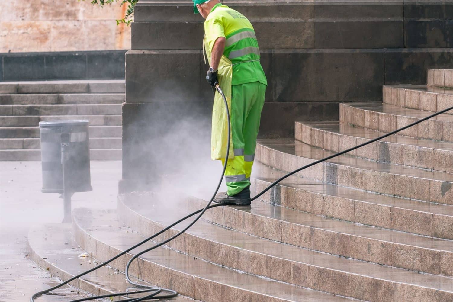 A worker washing stone steps with a pressure washer