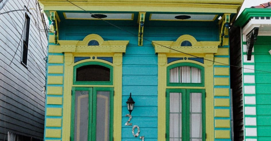 Colorful New Orleans shotgun house painted teal, lime, and green with ornate trim