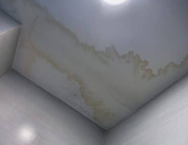 Brown water stain rings on a white ceiling after a leak